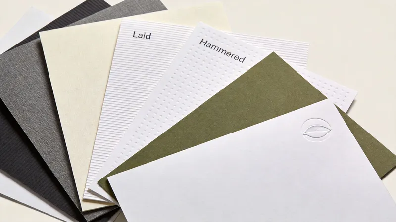 A fan of various textured paper samples displayed on a plain white background for professional printing.