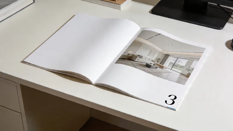 An open magazine lies on a white desk, displaying an interior design photograph and page number three.