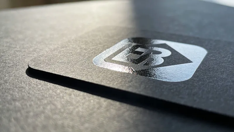 A close-up shot of a matte black business card featuring a shiny spot UV logo coating.